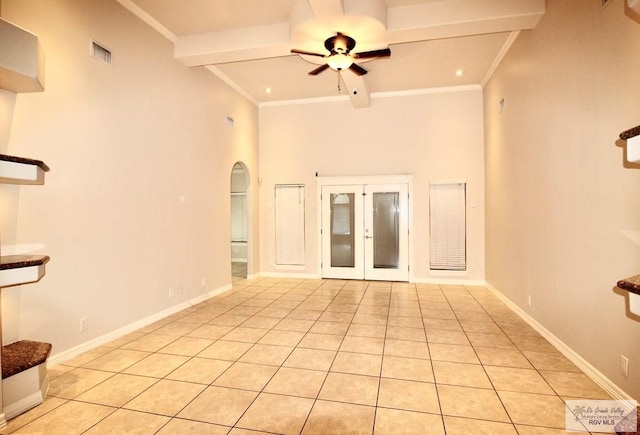 unfurnished living room with a towering ceiling, ornamental molding, ceiling fan, light tile patterned floors, and beamed ceiling