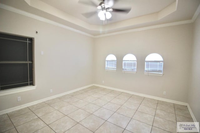 tiled spare room featuring a tray ceiling, ceiling fan, and ornamental molding