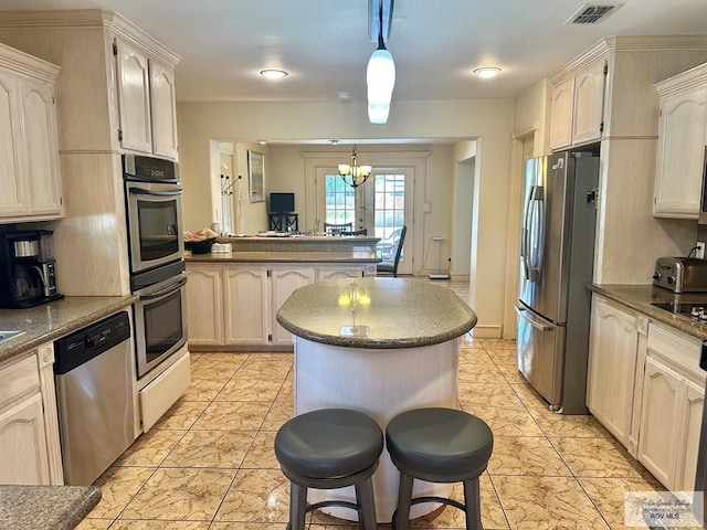 kitchen with an inviting chandelier, a peninsula, visible vents, appliances with stainless steel finishes, and pendant lighting