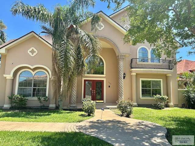 mediterranean / spanish home featuring a balcony, french doors, stucco siding, and a front lawn
