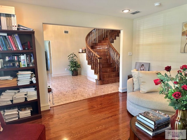 living area featuring stairs, visible vents, baseboards, and wood finished floors