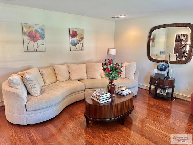 living room with wood finished floors, baseboards, and visible vents