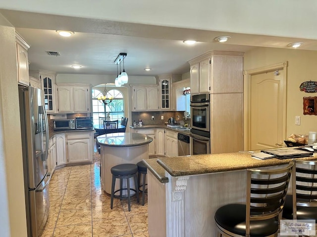 kitchen with tasteful backsplash, glass insert cabinets, visible vents, a breakfast bar area, and stainless steel appliances