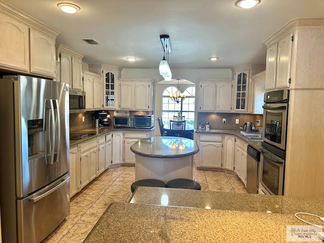 kitchen featuring visible vents, glass insert cabinets, an inviting chandelier, stainless steel appliances, and decorative backsplash