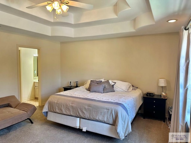 bedroom with a tray ceiling, connected bathroom, a ceiling fan, and carpet floors