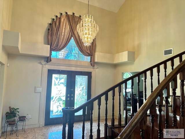 entryway featuring french doors, visible vents, a towering ceiling, and stairs