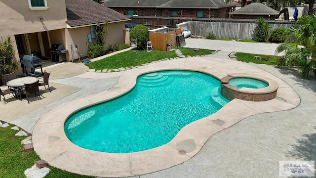 view of pool with area for grilling, an outdoor kitchen, a pool with connected hot tub, a patio, and fence