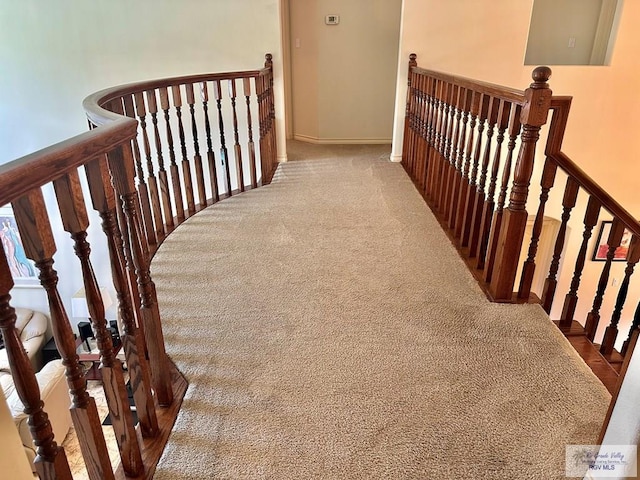 stairway featuring baseboards and carpet floors