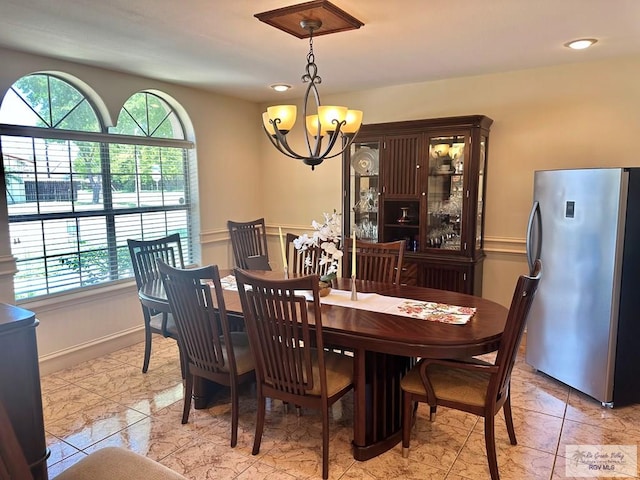 dining area with a chandelier, plenty of natural light, and marble finish floor