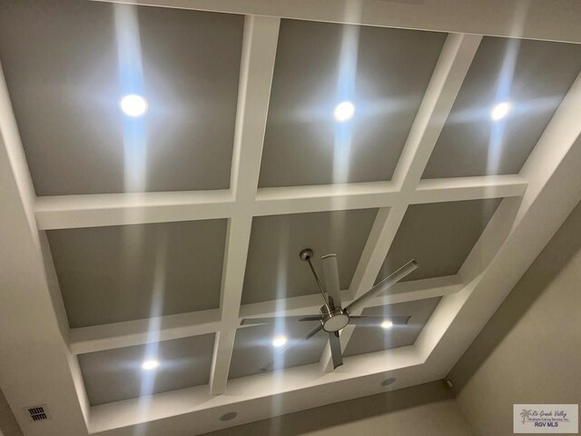 living room with coffered ceiling, a towering ceiling, and beamed ceiling