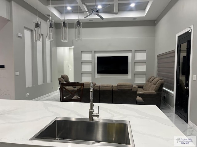 kitchen with sink, hanging light fixtures, coffered ceiling, light stone counters, and built in shelves