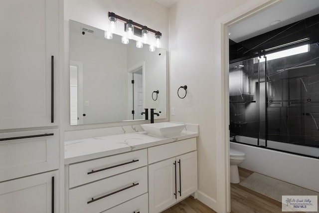full bath with vanity, toilet, wood finished floors, and enclosed tub / shower combo