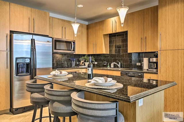 310 Padre Blvd Unit 1402, South Padre Island, TX 78597 - kitchen featuring stainless steel appliances, decorative backsplash, dark stone counters, a center island, and a kitchen breakfast bar