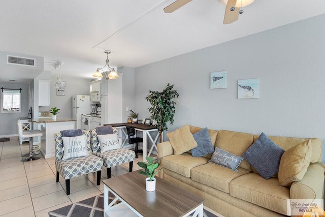 tiled living room with ceiling fan with notable chandelier