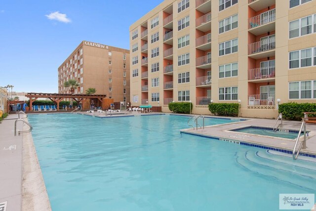 view of swimming pool with a community hot tub and a pergola