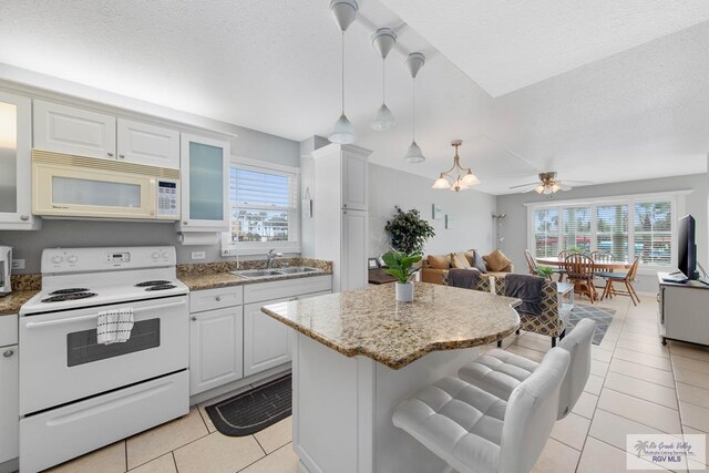 kitchen with ceiling fan with notable chandelier, white appliances, plenty of natural light, and sink