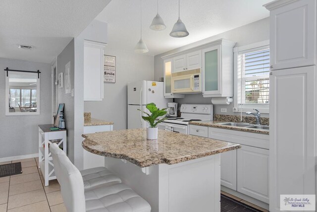 kitchen with white appliances, white cabinets, sink, hanging light fixtures, and a kitchen island