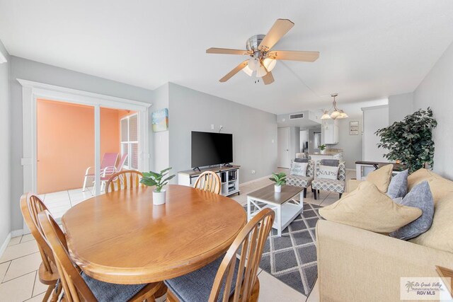 dining space featuring light tile patterned floors and ceiling fan with notable chandelier