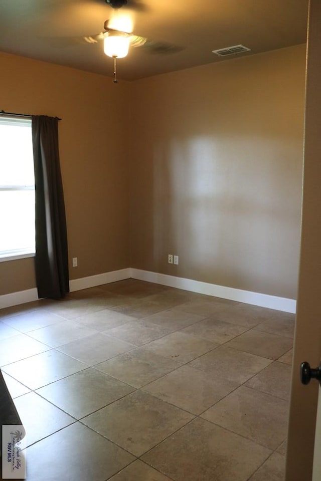 empty room with ceiling fan and light tile patterned floors