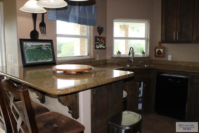 kitchen with light stone counters, sink, black dishwasher, and a wealth of natural light