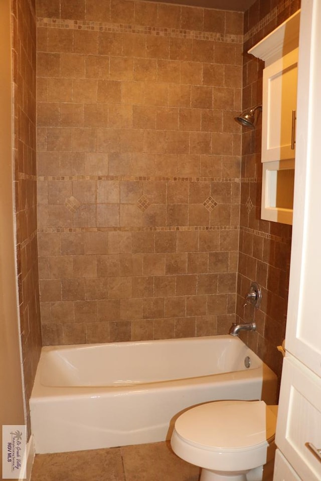 bathroom with tile patterned floors, tiled shower / bath combo, and toilet