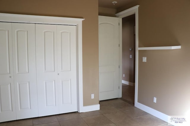 unfurnished bedroom with light tile patterned floors and a closet