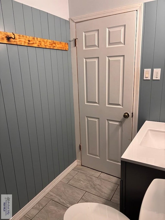 bathroom with vanity and wooden walls