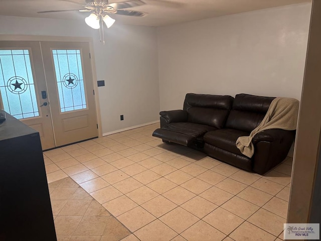 living area with baseboards, ceiling fan, and light tile patterned flooring
