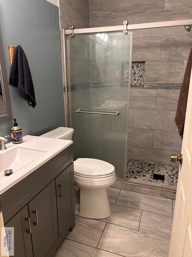 bathroom featuring vanity, marble finish floor, toilet, and a shower stall