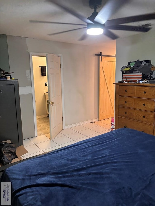 bedroom featuring a ceiling fan, baseboards, a barn door, and light tile patterned floors