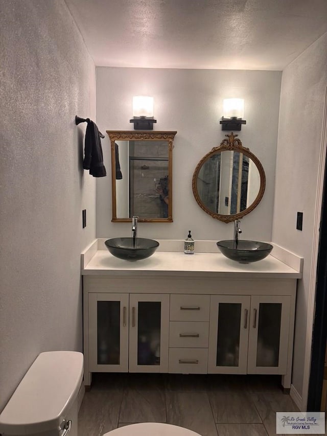bathroom with double vanity, a sink, marble finish floor, and toilet