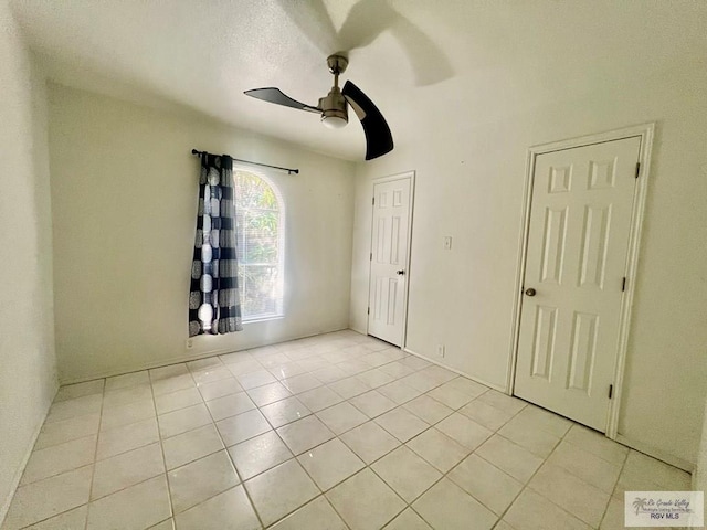 tiled empty room featuring ceiling fan