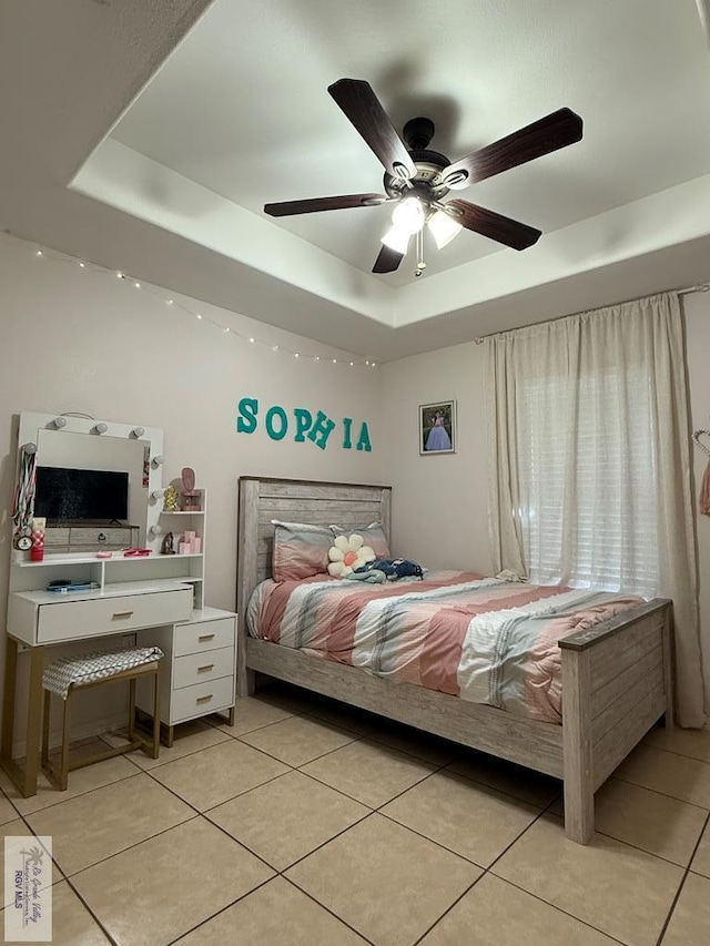 tiled bedroom featuring ceiling fan and a tray ceiling