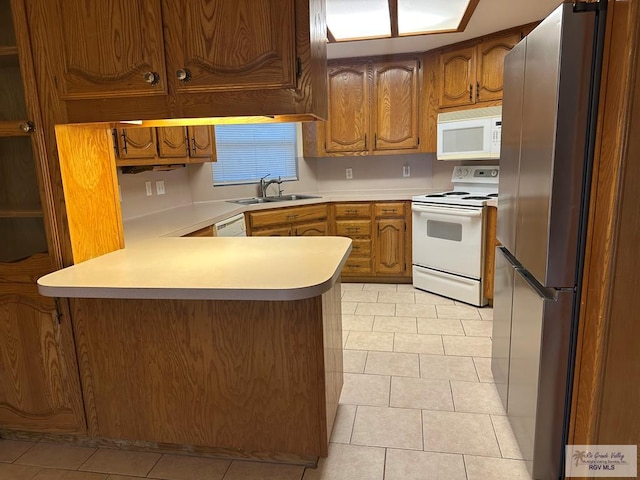 kitchen featuring sink, white appliances, kitchen peninsula, and light tile patterned floors