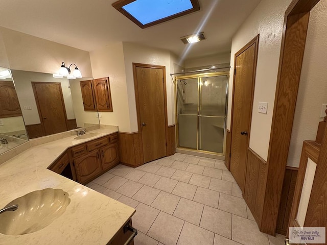 bathroom with vanity, an enclosed shower, tile patterned floors, and a skylight