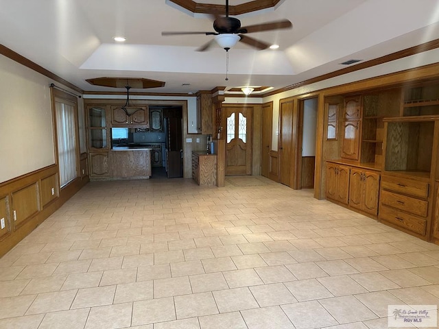 unfurnished living room featuring ceiling fan, ornamental molding, and a raised ceiling