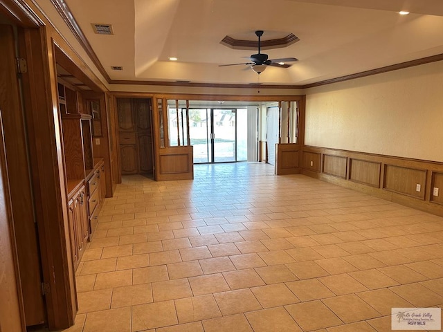 spare room with a raised ceiling, ornamental molding, light tile patterned floors, and ceiling fan