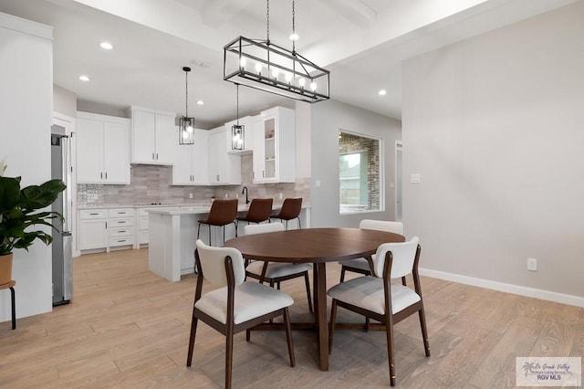 dining area with beam ceiling, sink, and light wood-type flooring