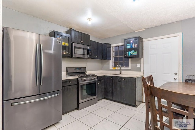 kitchen with stainless steel appliances, a textured ceiling, light tile patterned flooring, and sink