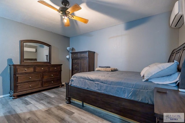 bedroom featuring light wood-type flooring, ceiling fan, and a wall mounted air conditioner