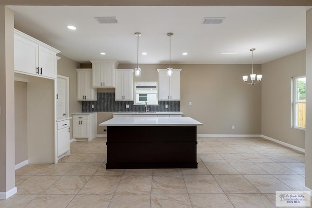 kitchen with white cabinets, sink, a kitchen island, and pendant lighting