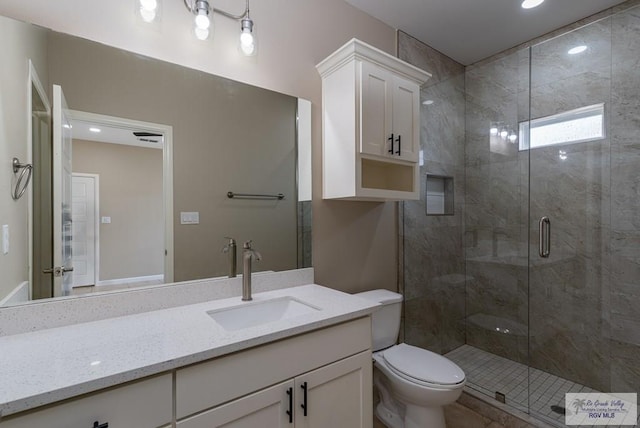 bathroom with vanity, toilet, and a shower with door