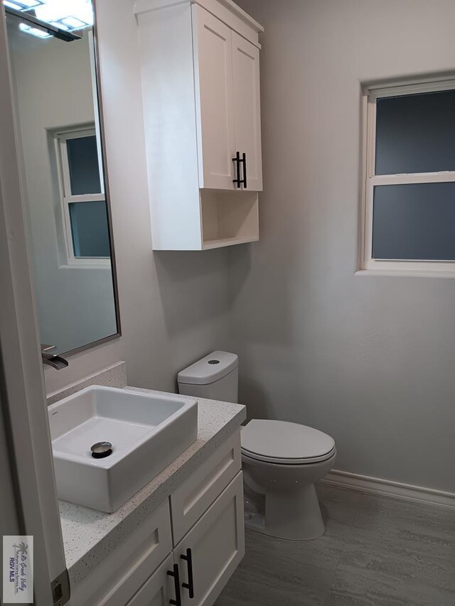 bathroom featuring wood-type flooring, vanity, and toilet