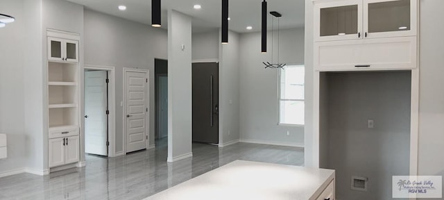 kitchen with hardwood / wood-style flooring, white cabinetry, hanging light fixtures, and a towering ceiling