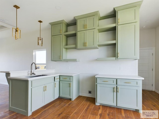 kitchen featuring decorative light fixtures, dark hardwood / wood-style floors, green cabinetry, and sink