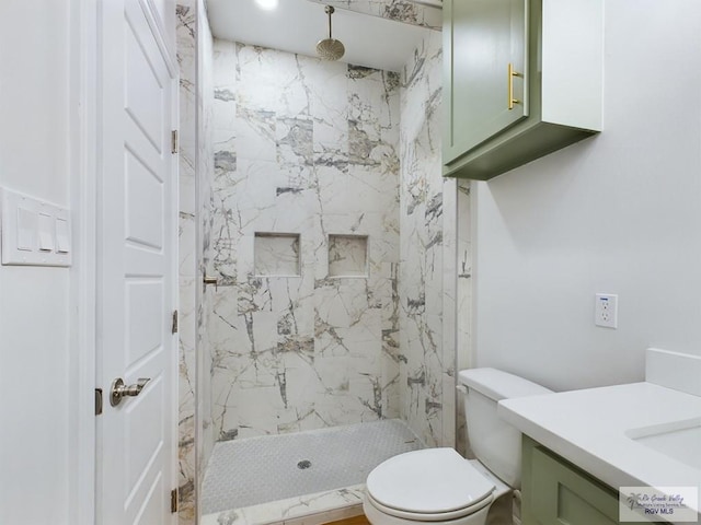 bathroom with vanity, toilet, and tiled shower