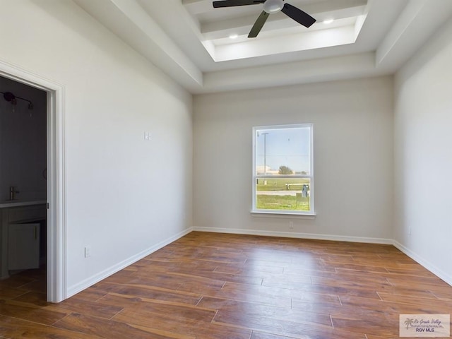 unfurnished room featuring a tray ceiling, ceiling fan, and dark wood-type flooring