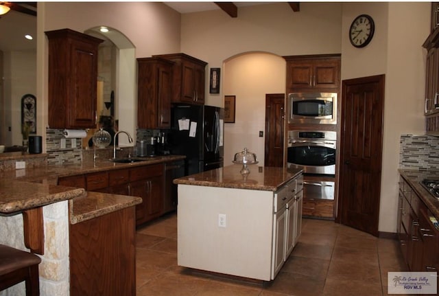 kitchen featuring sink, tasteful backsplash, a center island, dark tile patterned floors, and black appliances