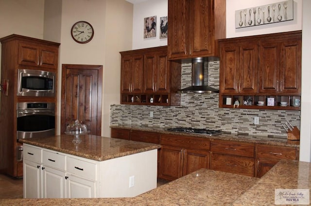 kitchen with tasteful backsplash, appliances with stainless steel finishes, wall chimney exhaust hood, and white cabinets