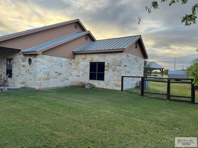 property exterior at dusk featuring a lawn